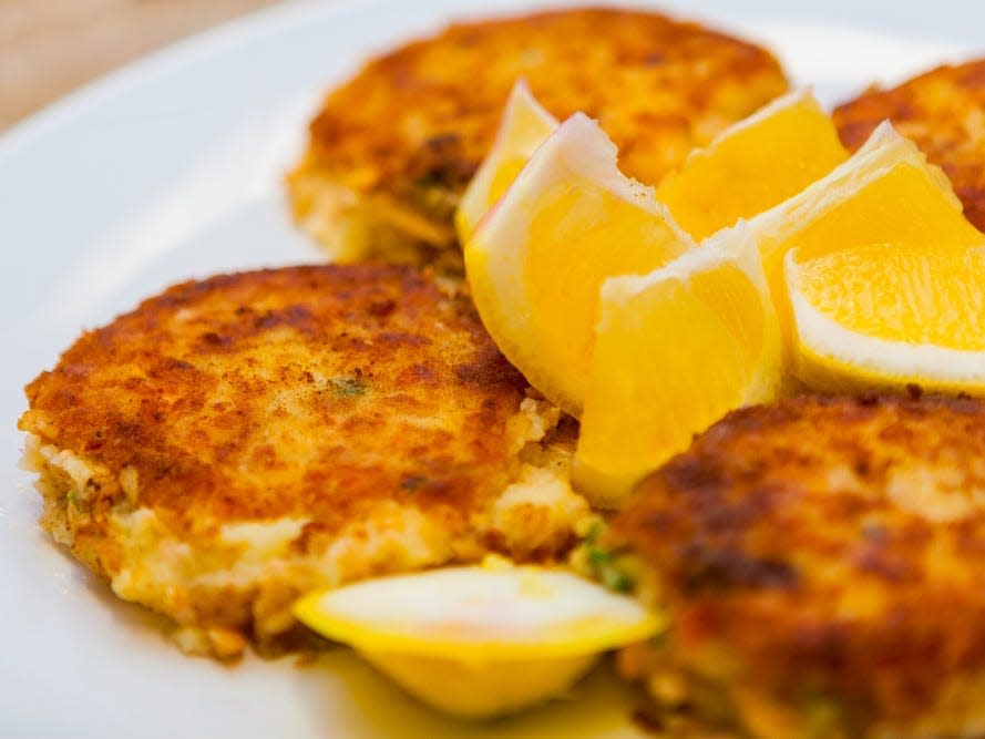 Crab cakes with lemon wedges on a white plate