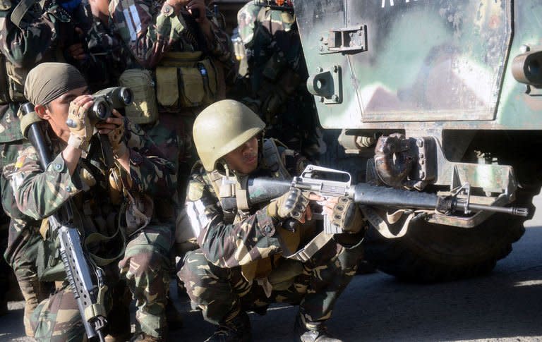 A Philippine soldier monitors the scene with binoculars while a colleague aims his weapon before an attempted assault on Muslim rebel positions as the stand-off enters its fifth day in Zamboanga City on September 13, 2013