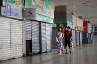 A man wearing a face mask walks by a closed mall amid the coronavirus disease (COVID-19) outbreak in Brasilia