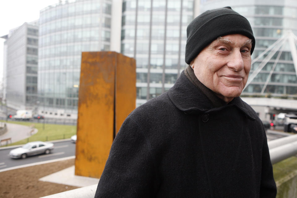 ARCHIVO - El famoso escultor estadounidense Richard Serra posa frente a "Slat", una escultura de acero de 1984, después de su reinstalación en La Defense, al oeste de París, el 15 de diciembre de 2008. Serra, conocido por convertir paredes curvas de acero oxidado y otros materiales maleables en obras de arte a gran escala que ahora están repartidas por todo el mundo, murió el martes 26 de marzo de 2024 en su casa en Long Island, Nueva York. Tenía 85 años. (Foto AP/Jacques Brinon, archivo)