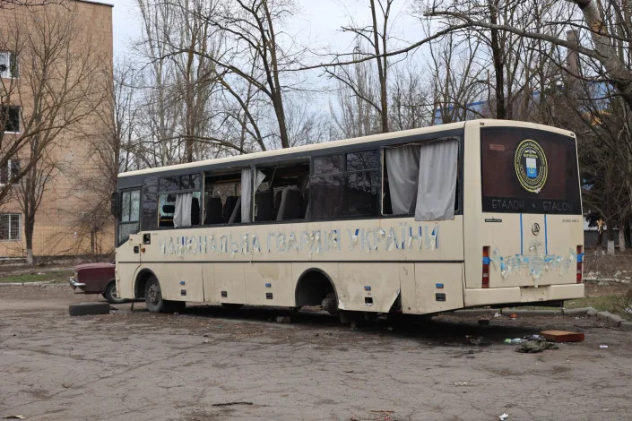 A military bus without one set of wheels and its previous designation painted out. 