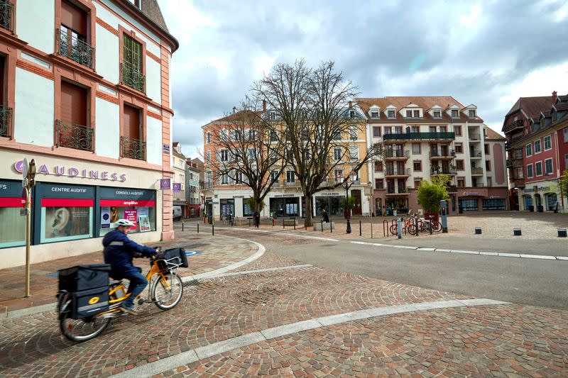 A postman cycles on the streets in Mulhouse