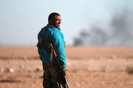 A Syrian Democratic Forces (SDF) fighter stands near rising smoke, north of Raqqa city, Syria November 6, 2016. REUTERS/Rodi Said