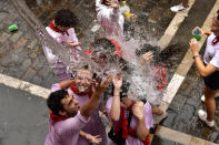 Water is thrown on revelers celebrating the launch of the 'Chupinazo' rocket, to mark the official opening of the 2022 San Fermin fiestas in Pamplona, Spain, Wednesday, July 6, 2022. The blast of a traditional firework opened Wednesday nine days of uninterrupted partying in Pamplona's famed running-of-the-bulls festival which was suspended for the past two years because of the coronavirus pandemic. (AP Photo/Alvaro Barrientos)