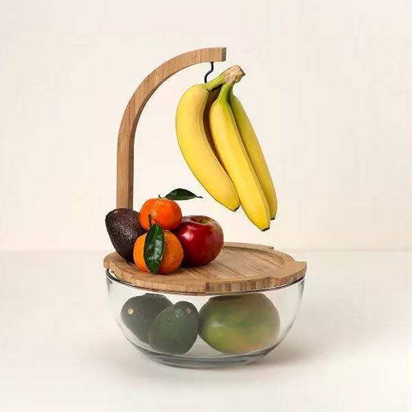 A fruit bowl with a hanging hook for bananas over a closed glass bowl.
