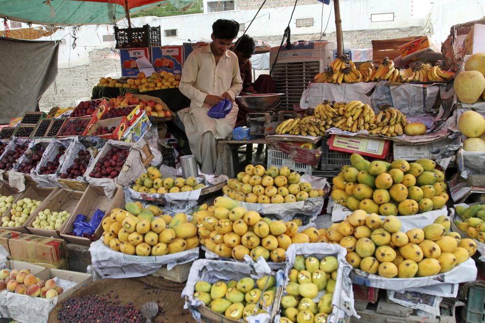 A fruit seller waits for customers at a market in Rojhan town, in Rajanpur, a district of Pakistan's Punjab province, Sunday, May 21, 2023. In Punjab, farms got a lucky break as the water enriched once-dry lands during the floods last year. (AP Photo/Asim Tanveer)