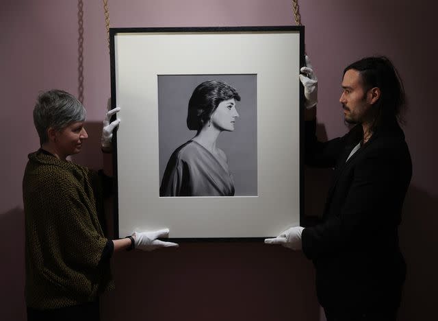 <p>Yui Mok/PA Images via Getty</p> Historic Royal Palaces conservators Ola Ruiz-Aguillo and Nelson Garcia hold a portrait of Diana, Princess of Wales, taken by photographer David Bailey in 1988, before the public opening of Life Through a Royal Lens exhibition at Kensington Palace in March 2022.