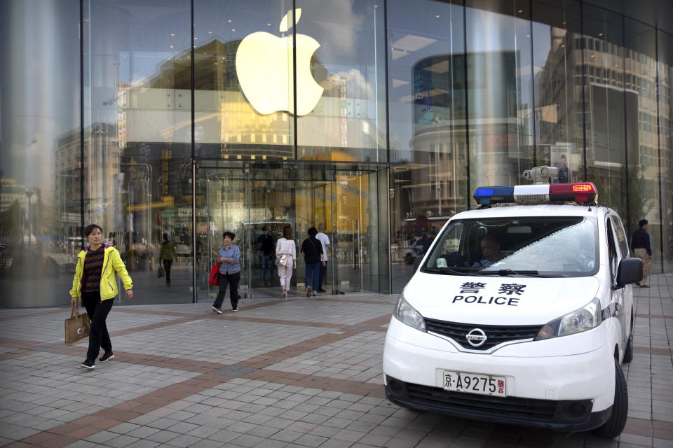 Chinese police sit in their vehicle as it is parked outside an Apple store at an outdoor shopping area in Beijing, Tuesday, Sept. 25, 2018. A Chinese trade envoy said Tuesday that talks with Washington are impossible while the United States "holds a knife" to Beijing's neck by imposing tariff hikes. (AP Photo/Mark Schiefelbein)