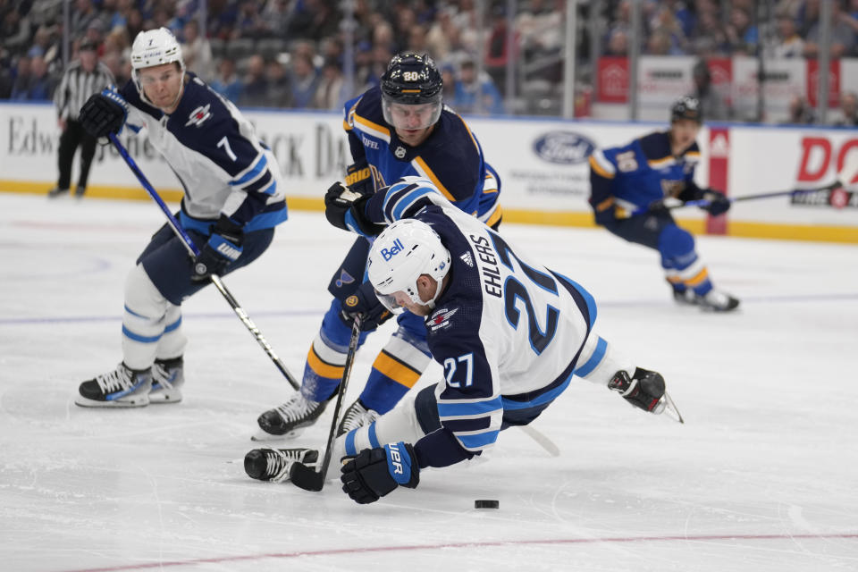 Winnipeg Jets' Nikolaj Ehlers (27) falls as teammate Vladislav Namestnikov (7) watches and St. Louis Blues' Brandon Saad defends during the first period of an NHL hockey game Tuesday, Nov. 7, 2023, in St. Louis. (AP Photo/Jeff Roberson)