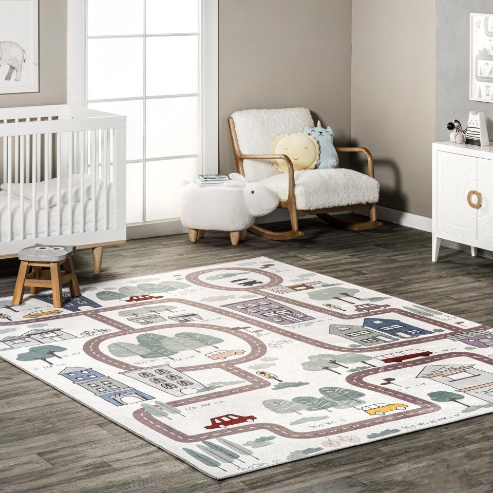 Children's playroom with a themed rug, crib, rocking chair, and a side table with toys