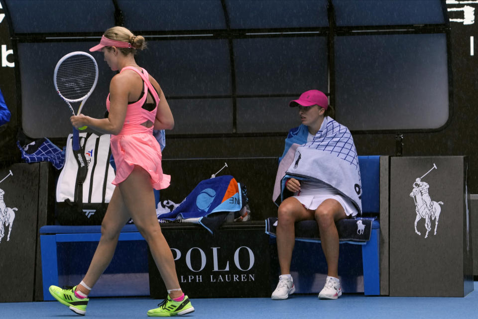 Iga Swiatek of Poland sits in her chair as rain falls during her second round match against Danielle Collins of the U.S. at the Australian Open tennis championships at Melbourne Park, Melbourne, Australia, Thursday, Jan. 18, 2024. (AP Photo/Andy Wong)