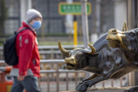 A man wearing a face mask walks past statues of bulls in Beijing, Friday, Feb. 28, 2020. Asian stock markets fell further Friday on spreading virus fears, deepening an global rout after Wall Street endured its biggest one-day drop in nine years. (AP Photo/Mark Schiefelbein)