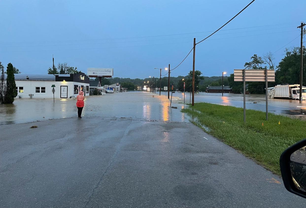 A woman looks over a flooded street in Marble Hill, Mo.