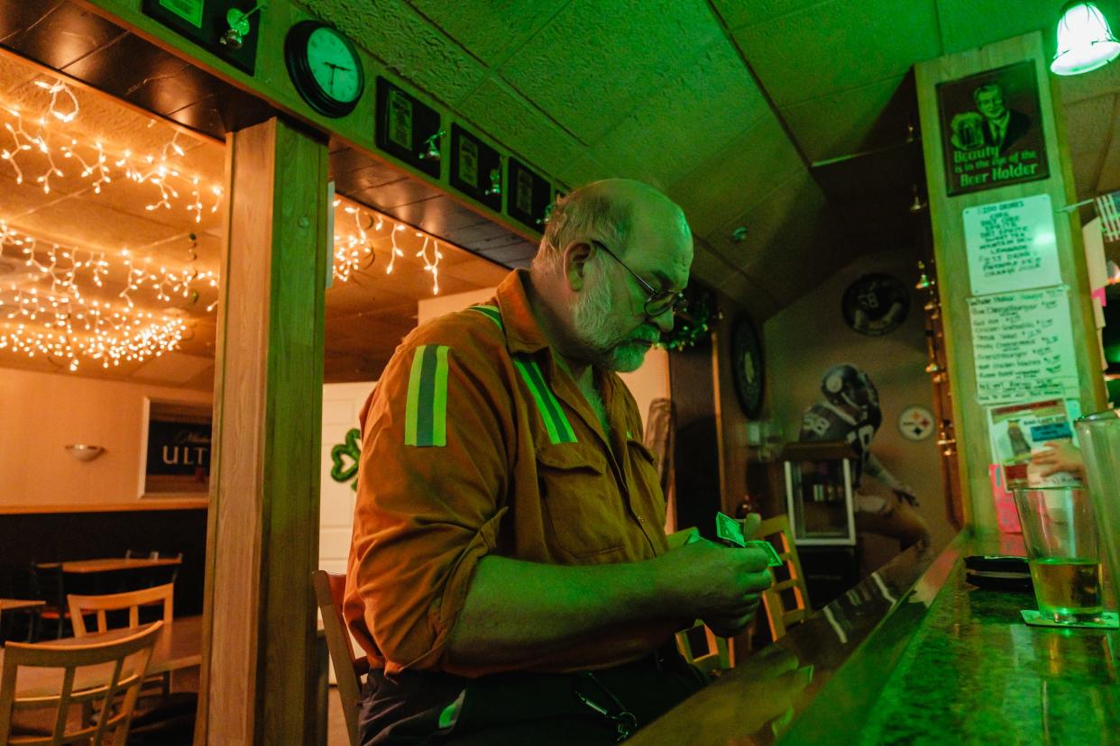 Keith Kruger, 66, who works as an electrician for Cleveland-Cliffs, pays for his beer at Irish Pub in Weirton, W.Va. Kruger, a 46-year veteran of the steel industry, was born and raised in Weirton.