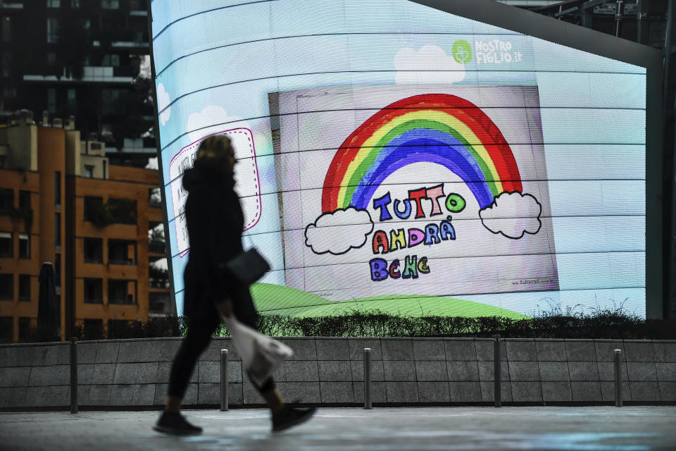 A woman walks past a billboard reading "Everything will be alright", in Milan, Italy. The nationwide lockdown to slow coronavirus is still early days for much of Italy, but Italians are already are showing signs of solidarity. This week, children’s drawings of rainbows are appearing all over social media as well as on balconies and windows in major cities ready, ‘’Andra’ tutto bene,’’ Italian for ‘’Everything will be alright.’’ For most people, the new coronavirus causes only mild or moderate symptoms. For some, it can cause more severe illness, especially in older adults and people with existing health problems. (Claudio Furlan/LaPresse via AP)