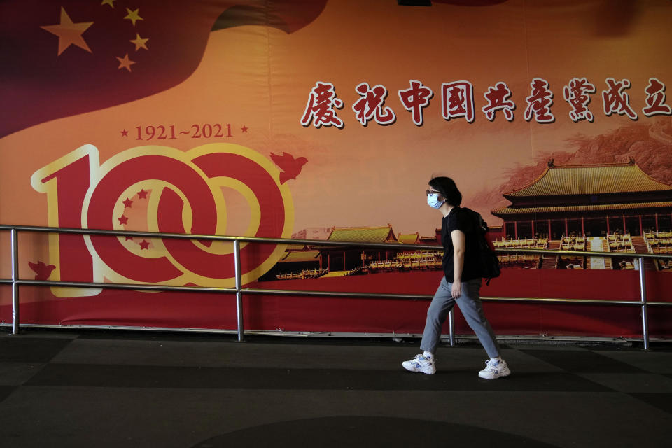 A woman walks past a poster marking the 100th anniversary of the founding of the ruling Chinese Communist Party, in Hong Kong, Wednesday, Sept. 8, 2021. Travelers arriving in Hong Kong from mainland China will no longer need to quarantine, Hong Kong's top official said Tuesday, Sept. 7, 2021, easing curbs imposed after outbreaks of the coronavirus on the mainland. (AP Photo/Kin Cheung)