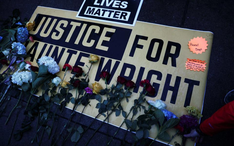 Flowers are laid on a sign as protesters rally outside the Brooklyn Center - Reuters