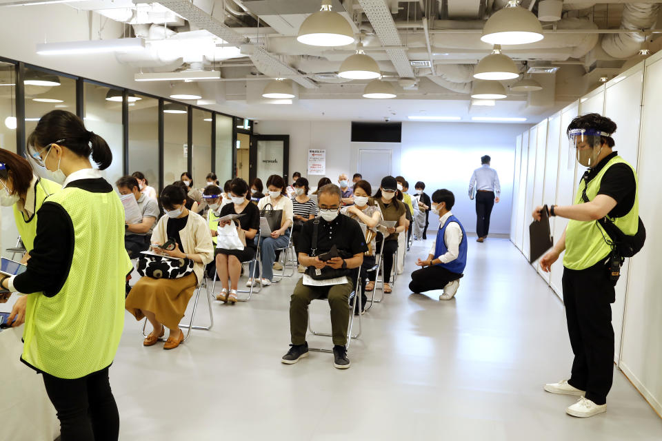 Medical workers wait to get Moderna's COVID-19 vaccine at an inoculation site set up by Japanese technology company SoftBank Group Corp. at a WeWork office Tuesday, June 15, 2021, in Tokyo. Japanese companies have joined the effort to speed up the country’s lagging coronavirus vaccine rollout before the Tokyo Olympics begin next month. (AP Photo/Yuri Kageyama)