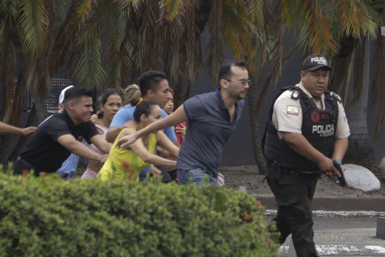 La policía evacua al personal de la estación de televisión TC después de que un grupo de hombres armados irrumpiera en su set durante una transmisión en vivo, en Guayaquil, Ecuador, el martes 9 de enero de 2024.