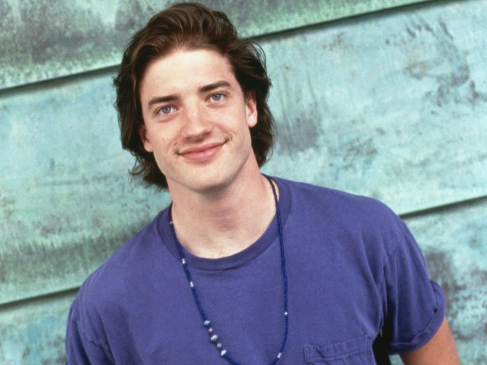 Brendan Fraser poses for photos in a blue t-shirt and jeans.