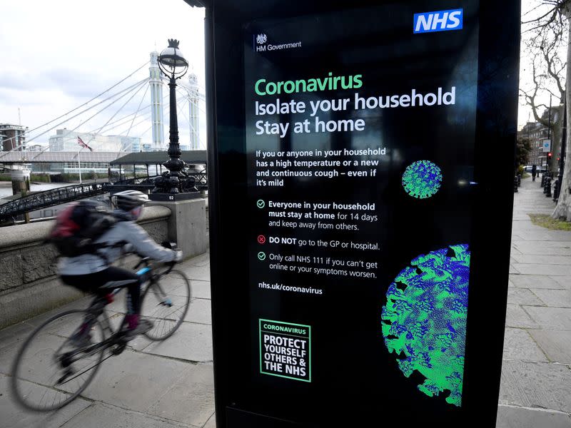 FILE PHOTO: A cyclist rides past a UK government public health campaign poster as the spread of the coronavirus disease (COVID-19) continues, in London