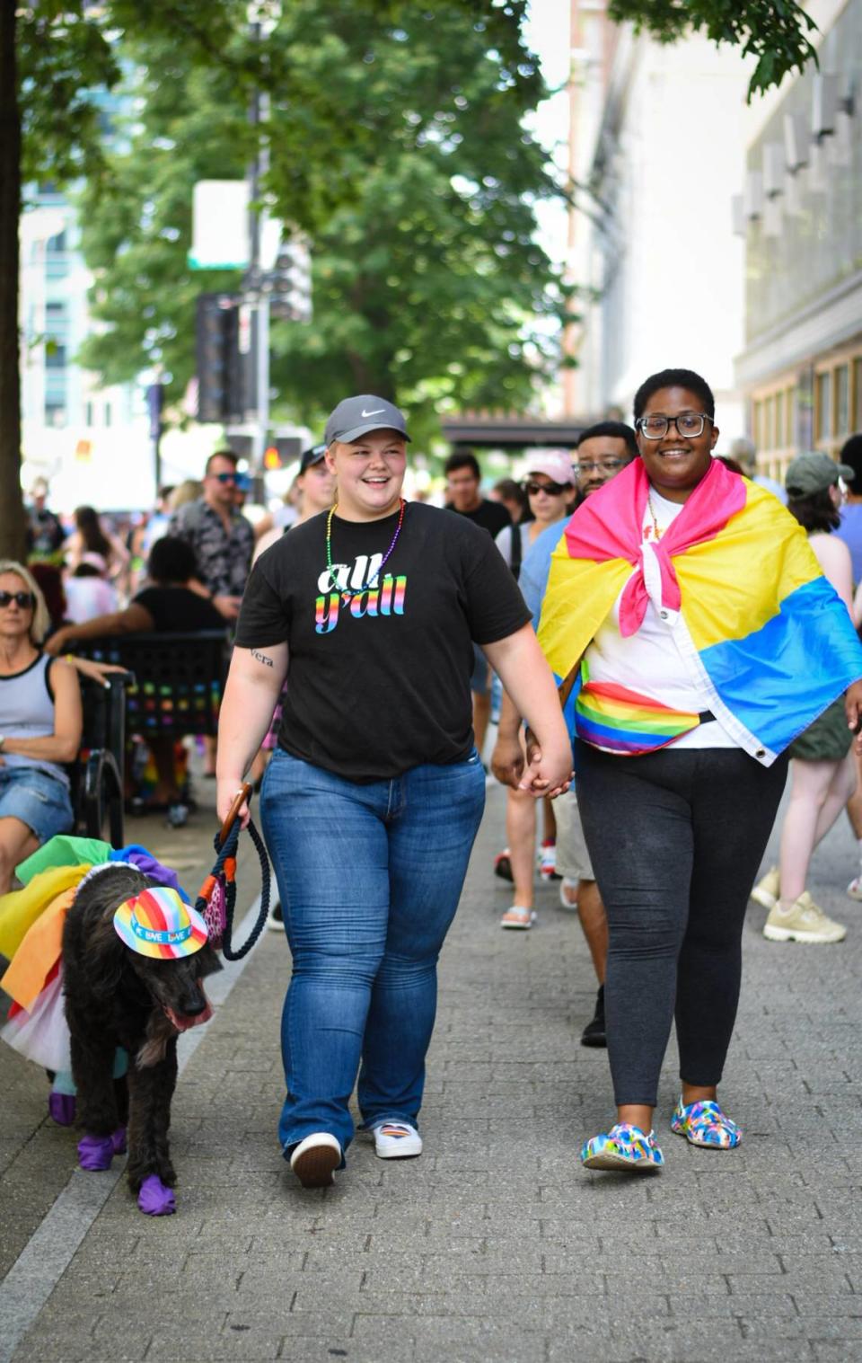 Asya Cofield (right) and Danielle Wilshire (center) walk their dressed-up dog Charlie (left) along Fayetteville Street at the Out! Raleigh Pride festival in downtown Raleigh on Saturday, June 25, 2022.