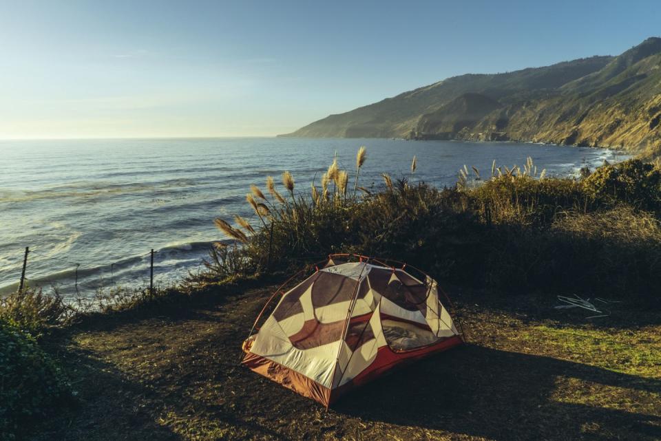 tent on field by sea during sunset