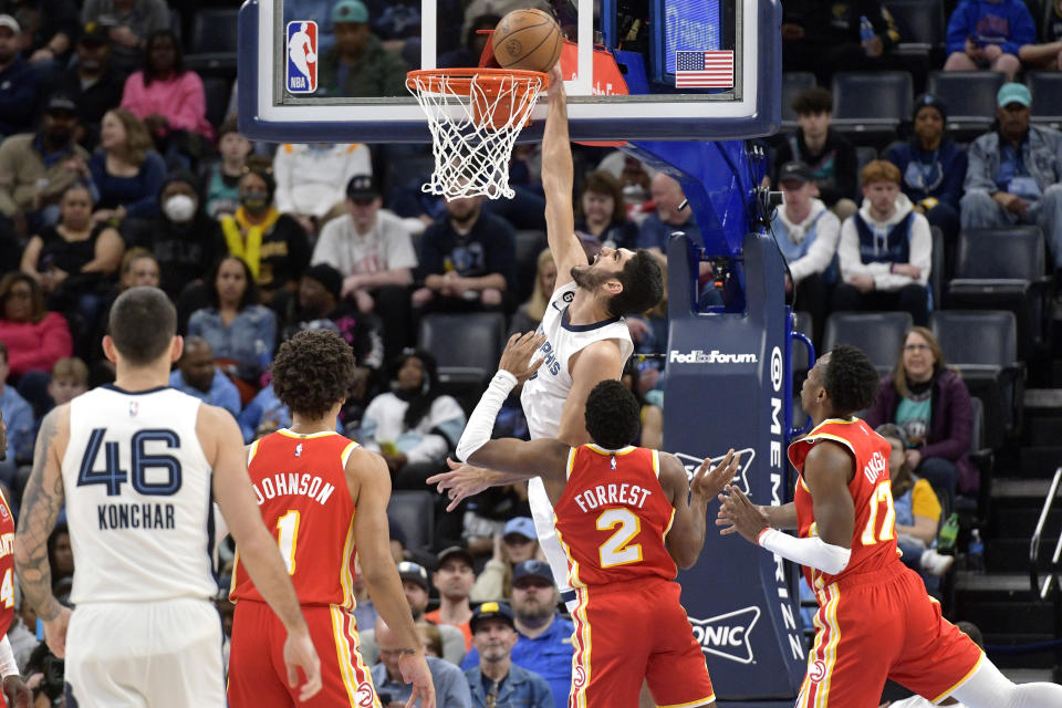 Memphis Grizzlies forward Santi Aldama, center top, goes up to dunk against Atlanta Hawks guard Trent Forrest (2) in the first half of an NBA basketball game Monday, Dec. 12, 2022, in Memphis, Tenn. (AP Photo/Brandon Dill)