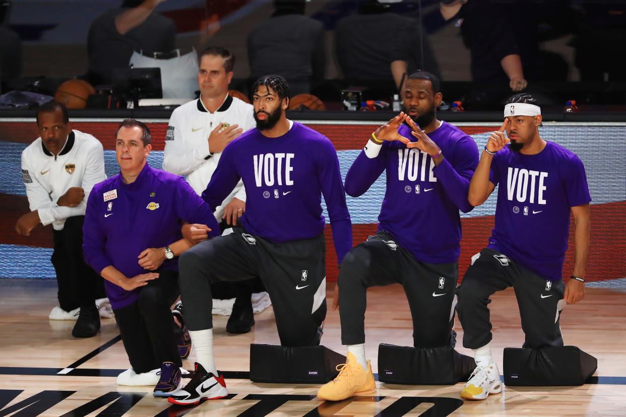 LAKE BUENA VISTA, FLORIDA - OCTOBER 11: LeBron James #23 of the Los Angeles Lakers, Anthony Davis #3 of the Los Angeles Lakers and Frank Vogel of the Los Angeles Lakers kneel during the National Anthem prior to the start of the game aMiami Heat in Game Six of the 2020 NBA Finals at AdventHealth Arena at the ESPN Wide World Of Sports Complex on October 11, 2020 in Lake Buena Vista, Florida. NOTE TO USER: User expressly acknowledges and agrees that, by downloading and or using this photograph, User is consenting to the terms and conditions of the Getty Images License Agreement.  (Photo by Mike Ehrmann/Getty Images)