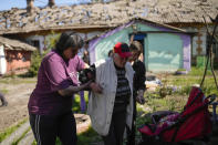 Local residents gather outside their heavily damaged house, background, after a Russian strike in Pokrovsk, eastern Ukraine, Wednesday, May 25, 2022. Two rockets struck the eastern Ukrainian town of Pokrovsk, in the Donetsk region early Wednesday morning, causing at least four injuries. (AP Photo/Francisco Seco)