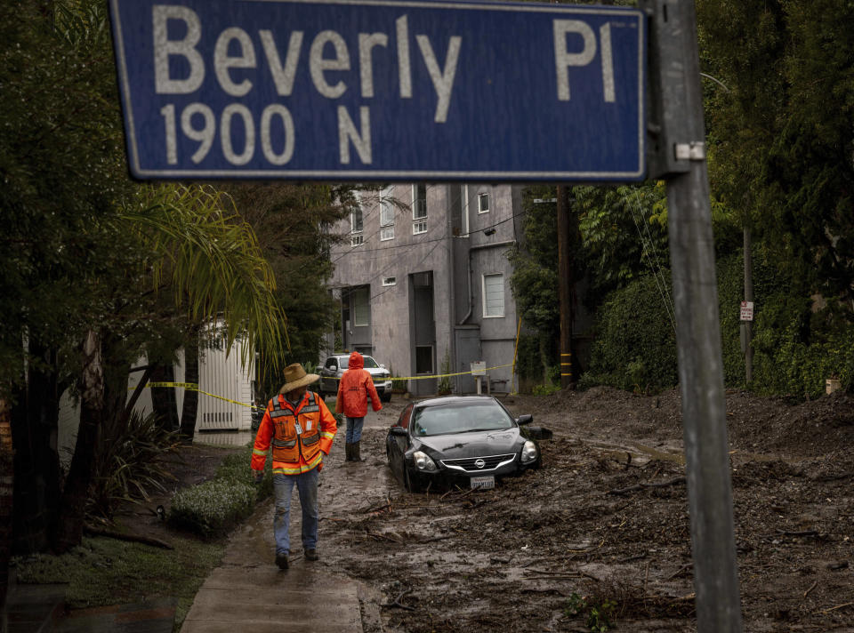 Workers survey a mudslide Tuesday, Feb. 6, 2024, in the Beverly Crest area of Los Angeles. (AP Photo/Ethan Swope)