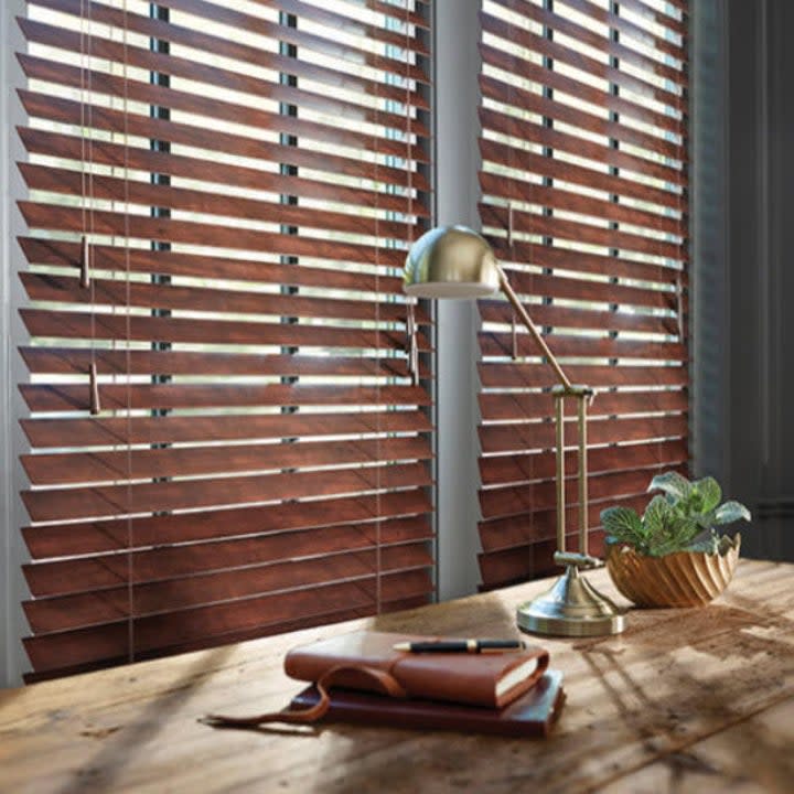 dark wooden blinds in front of wooden desk