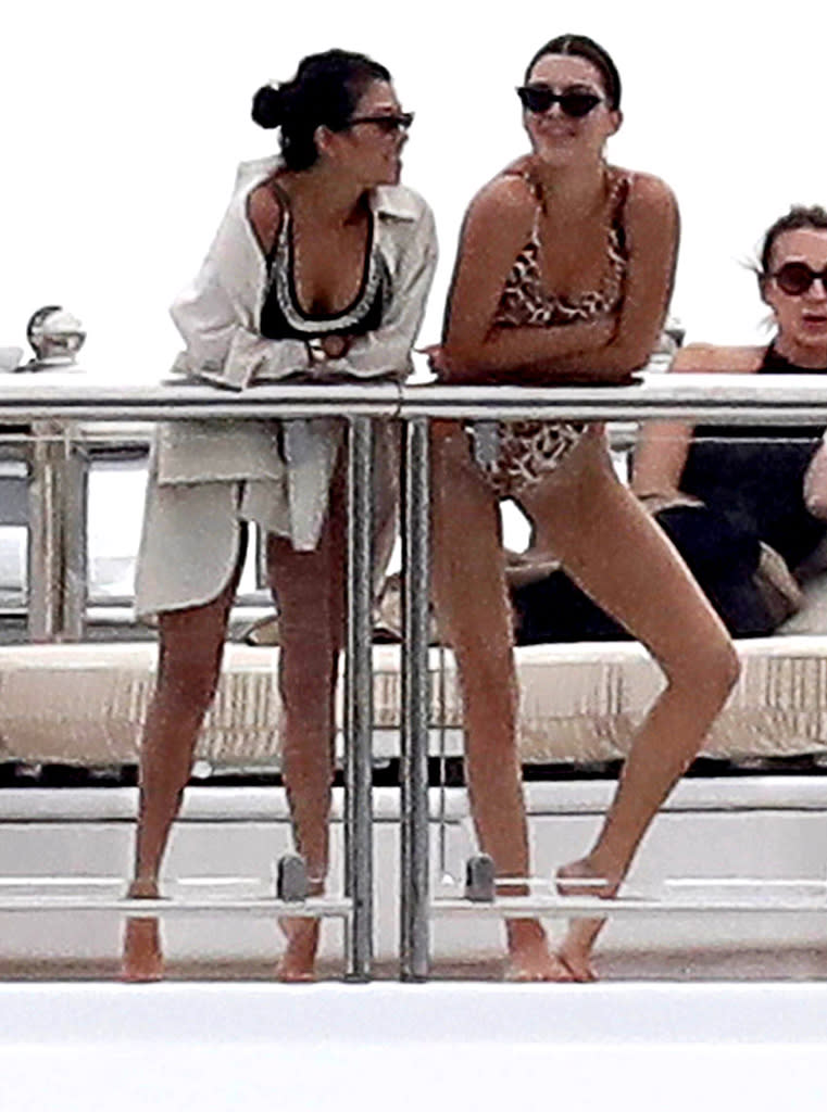 <p>Kendall rocked a leopard-print one-piece with cat-eye sunglasses, while Kourtney opted for a more demure black suit with silver trim as they chatted by the water. (Photo: BACKGRID) </p>