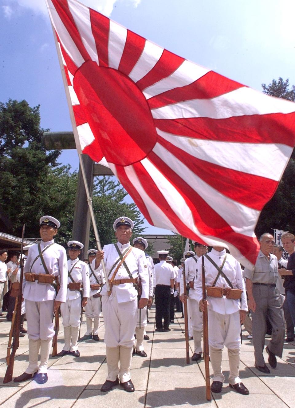 In front of the flag of the Rising Sun, World War II veterans in Imperial Navy uniforms pray for the war-dead at the Yasukuni Shrine in Tokyo 15 August 1999, on the 54th anniversary of Japan's surrender. (Toru Yamanaka/AFP via Getty Images)