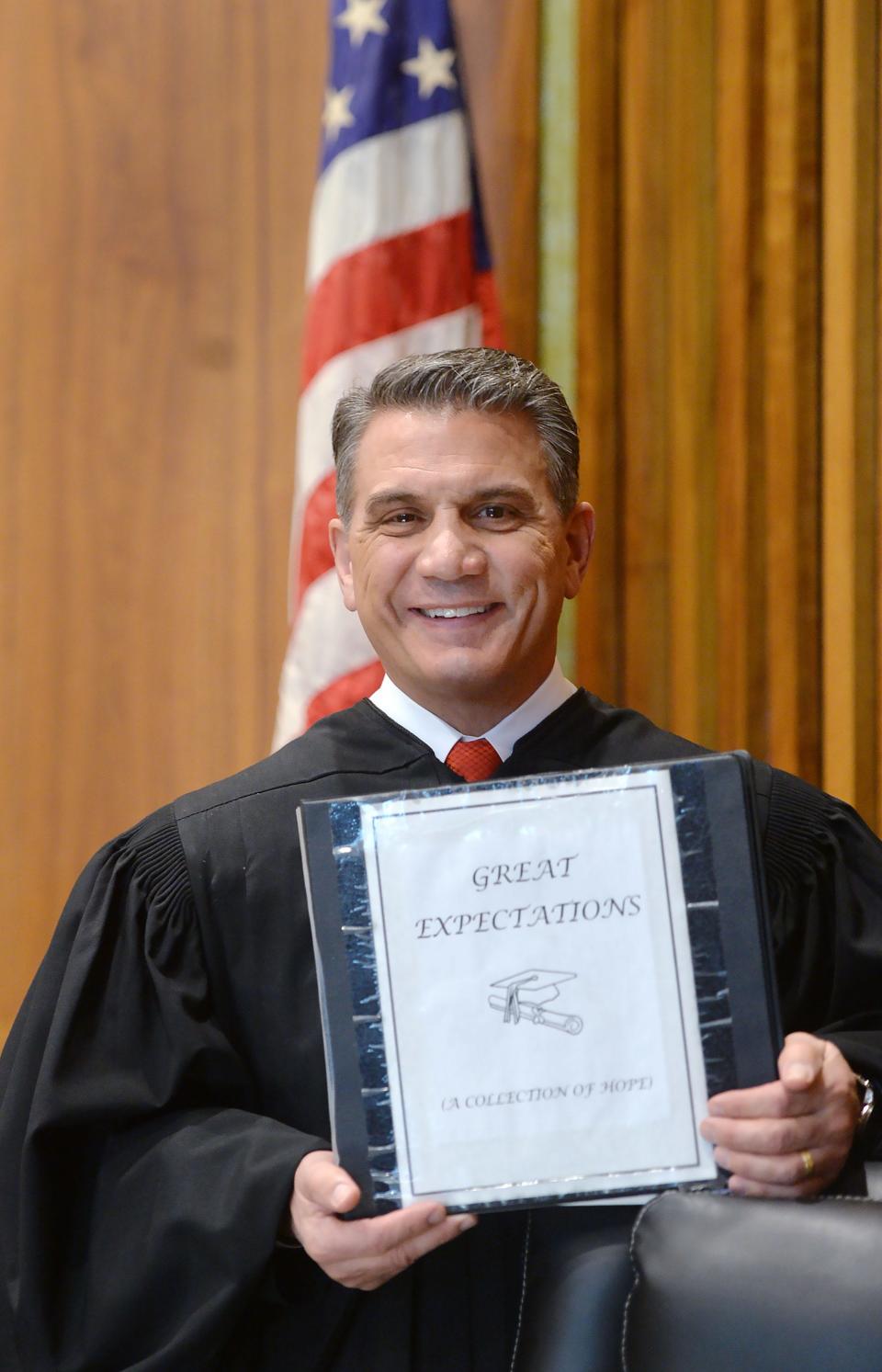 Erie County Judge John Trucilla holds a binder of diplomas and certificates from young people he has helped by requiring them to earn a GED or diploma before they can be discharged from court supervision. Trucilla was shown at the Erie County Courthouse in Erie on Feb. 29, 2024. Trucilla is calling for the creation of a local GED program for youth.