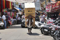 An Indian laborer talks on his mobile phone as he transports a refrigerator on his back at a market in Jammu, India, Sunday, June 7, 2020. India whose coronavirus caseload is fifth highest in the world has partially restored trains and domestic flights and allowed reopening of shops and manufacturing. (AP Photo/Channi Anand)