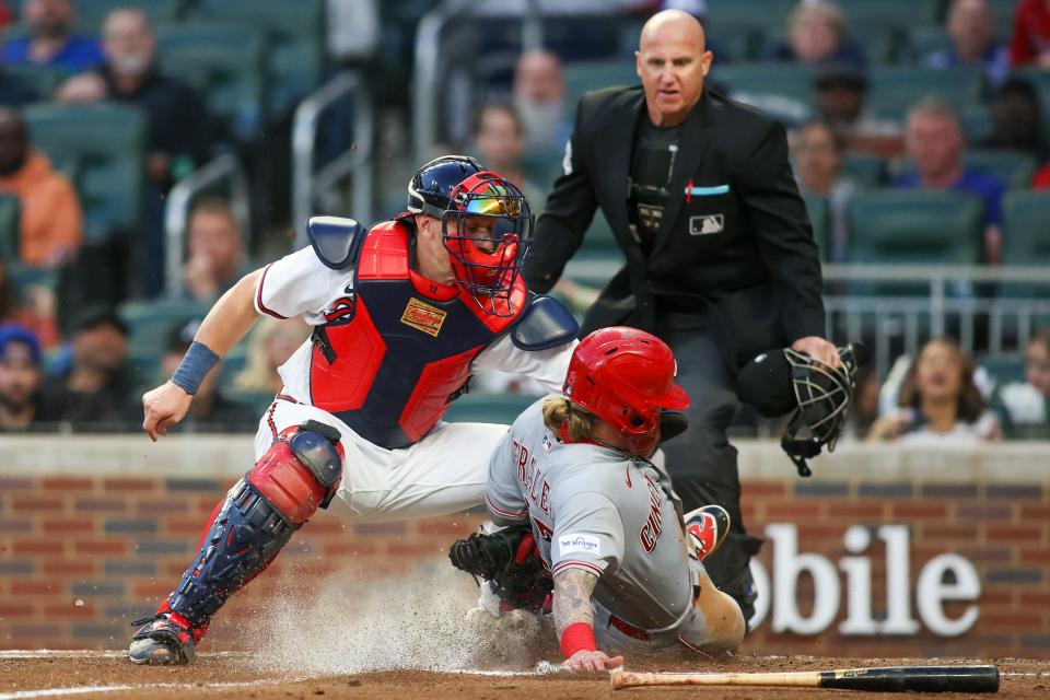 Reds left fielder Jake Fraley (27) slides safely past the tag of Atlanta Braves catcher Sean Murphy (left) in the third inning at Truist Park on Tuesday.