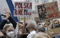 Women's rights activists hold placards protest against recent tightening of Poland's restrictive abortion law in front of the parliament building as inside, guards had to be used to shield right-wing ruling party leader Jaroslaw Kaczynski from angry opposition lawmakers, in Warsaw, Poland, Wednesday, Oct. 28, 2020. Massive nationwide protests have been held ever since a top court ruled Thursday that abortions due to fetal congenital defects are unconstitutional.(AP Photo/Czarek Sokolowski)