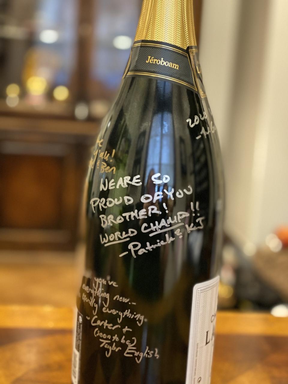 An unopened bottle of champagne signed by friends with congratulatory messages