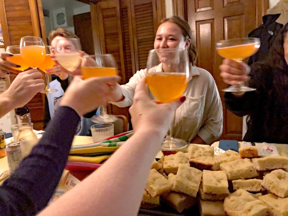 whole table cheersing with orange mocktails at dinner with friends dinner party