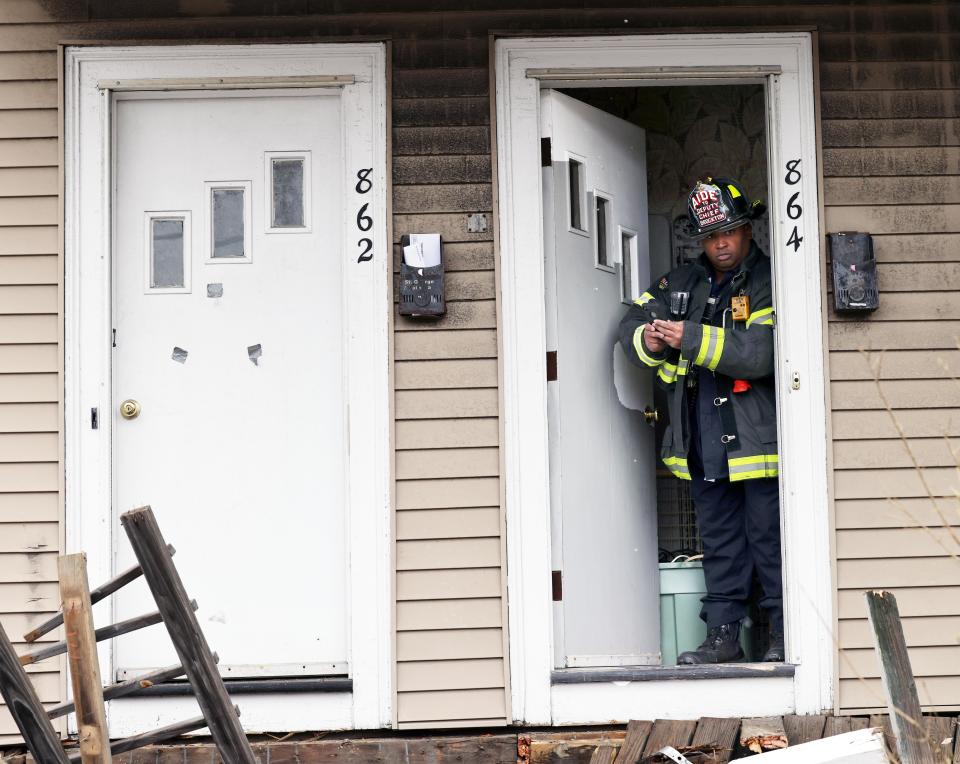 A firefighter assesses the damage to the home after a car struck a house at 862-864 Crescent St. in Brockton on Tuesday, Jan. 25, 2022.