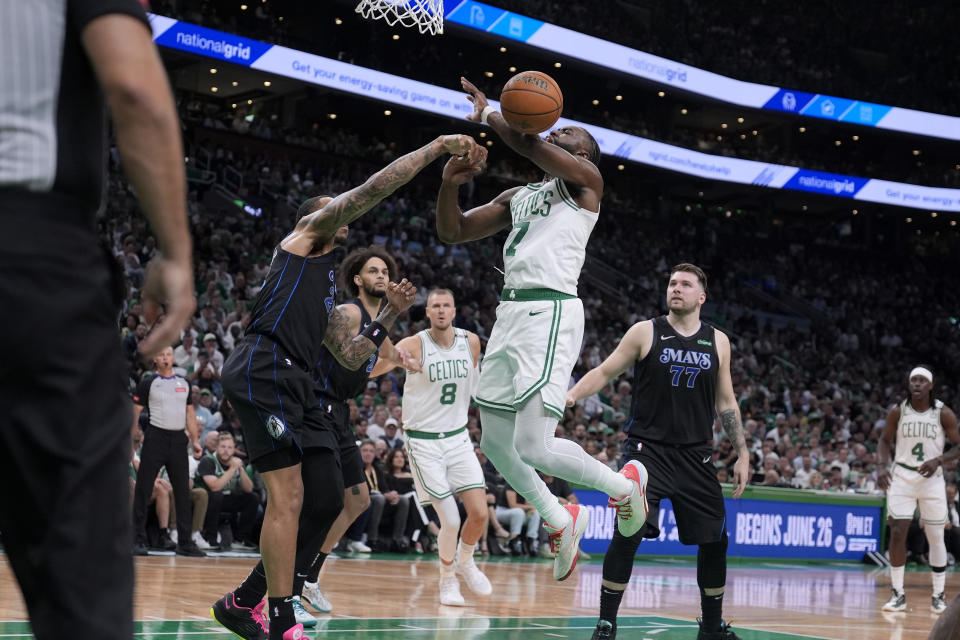 Dallas Mavericks forward P.J. Washington, left, fouls Boston Celtics guard Jaylen Brown, center, during the first half of Game 1 of basketball's NBA Finals on Thursday, June 6, 2024, in Boston. (AP Photo/Charles Krupa)