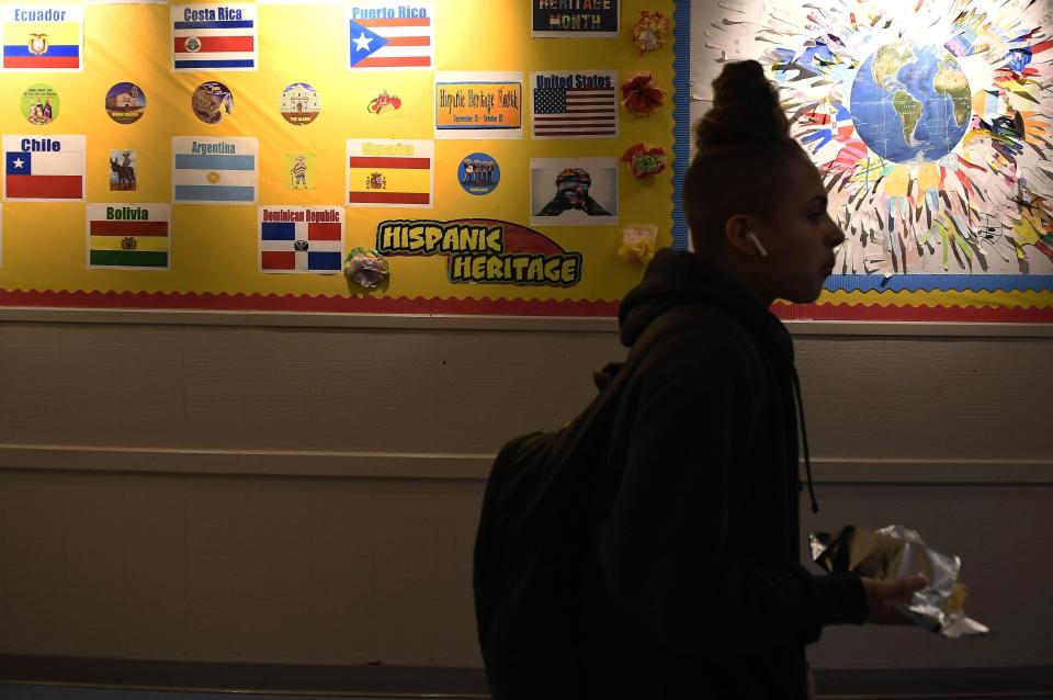 In this Nov. 7, 2019, photo, a student walks past an Hispanic Heritage display in the hallway at Crosby High School in Waterbury, Conn. While students in the Waterbury public school district are predominantly black and Hispanic, the vast majority of its educators, as in school districts across the country, are white. (AP Photo/Jessica Hill)