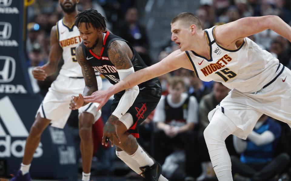 Houston Rockets guard Ben McLemore, font left, pursues the ball with Denver Nuggets center Nikola Jokic in the first half of an NBA basketball game Sunday, Jan. 26, 2020, in Denver. (AP Photo/David Zalubowski)