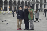 Tourists wearing protective masks take selfies in St. Mark's square in Venice, Italy, Tuesday, Feb. 25, 2020. Italy has been scrambling to check the spread of Europe's first major outbreak of the new viral disease amid rapidly rising numbers of infections and calling off the popular Venice Carnival and closing tourist attractions. (AP Photo/Renata Brito)