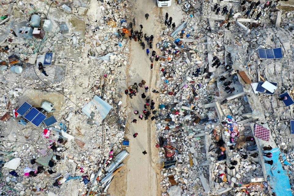 Residents searching for victims and survivors amid the rubble of collapsed buildings in the village of Besnia, Syria.