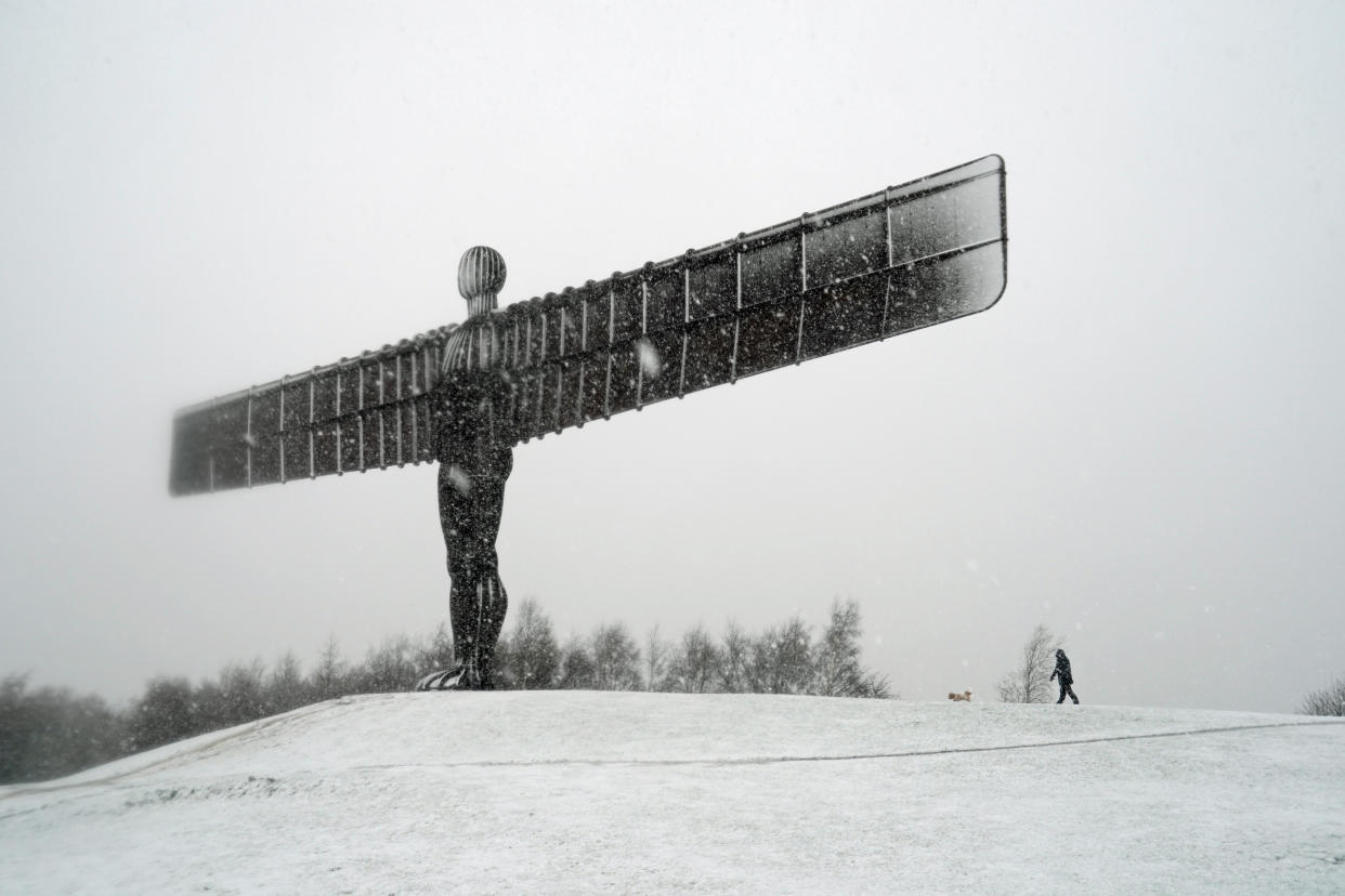 A man walks his dog in wintry conditions around the Angel of the North, near Gateshead, Tyne and Wear, after overnight snow hit parts of the UK. (Photo by Owen Humphreys/PA Images via Getty Images)