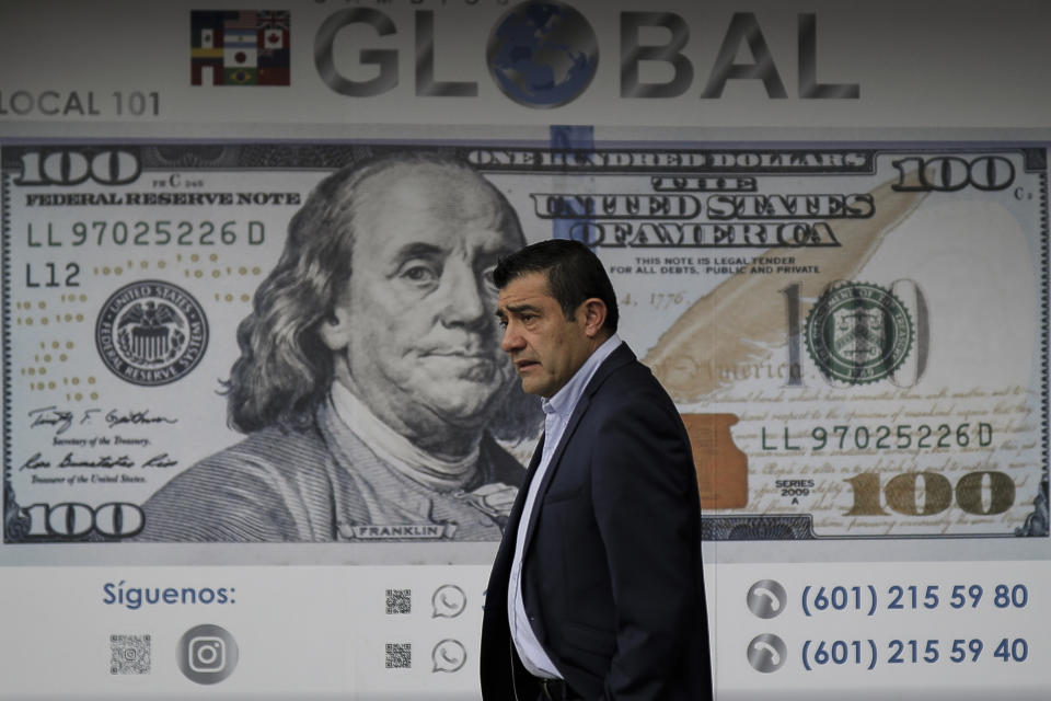 A man stands in front of a money exchange agency featuring an oversized U.S. bill in Bogota, Colombia, Tuesday, June 21, 2022, two days after the presidential election. The election of Gustavo Petro, a former guerrilla, as Colombia’s first leftist president is likely to test the U.S.’ special relationship with its major non-NATO ally like never before. (AP Photo/Ivan Valencia)