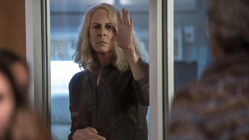 an image from Halloween Ends shows Laurie Strode looking sadly through a window