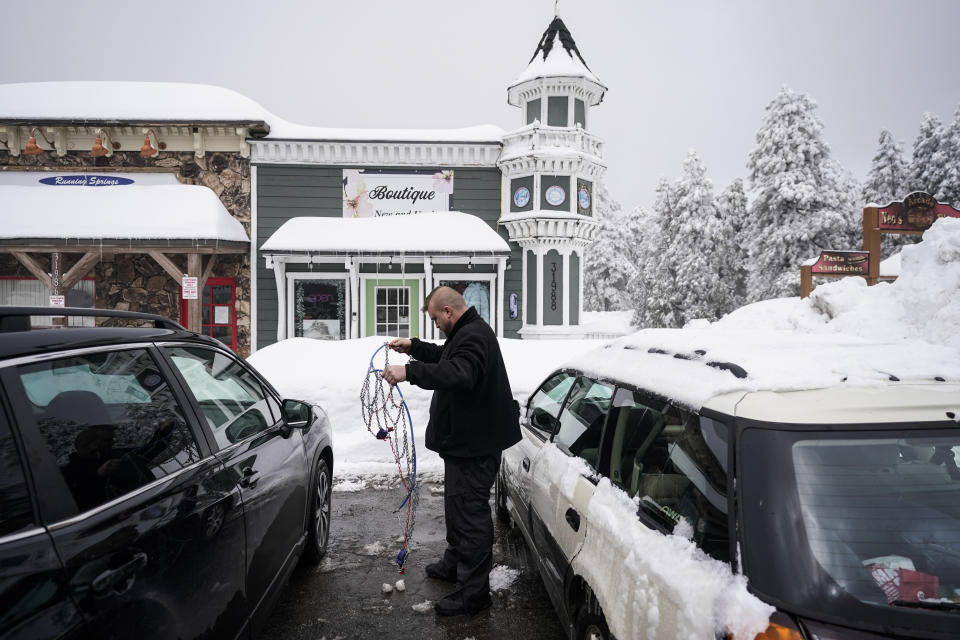 Sean Angus prepares his snow chain in Running Springs, Calif., Tuesday, Feb. 28, 2023. Beleaguered Californians got hit again Tuesday as a new winter storm moved into the already drenched and snow-plastered state, with blizzard warnings blanketing the Sierra Nevada and forecasters warning residents that any travel was dangerous. (AP Photo/Jae C. Hong)